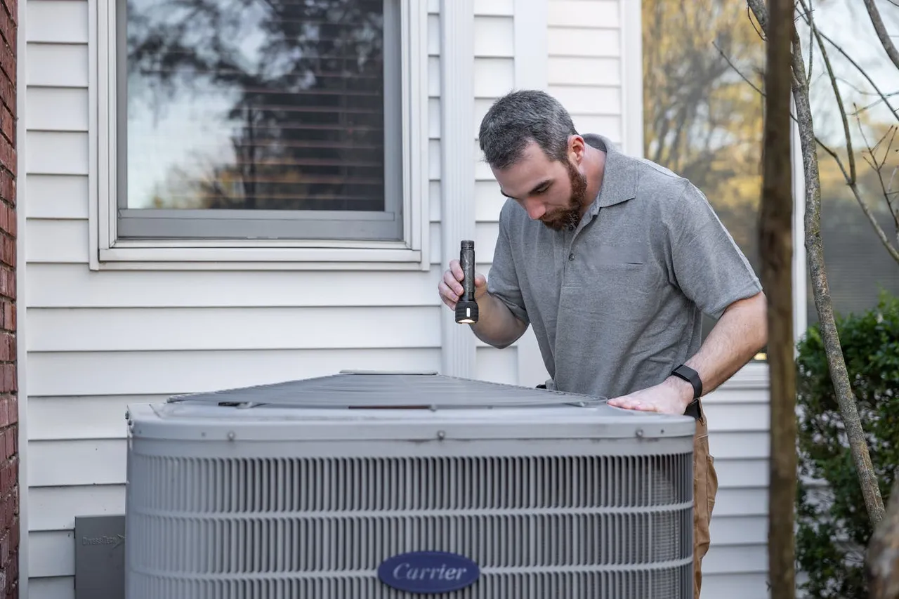 HVAC technician inspecting a residential Carrier condenser unit
