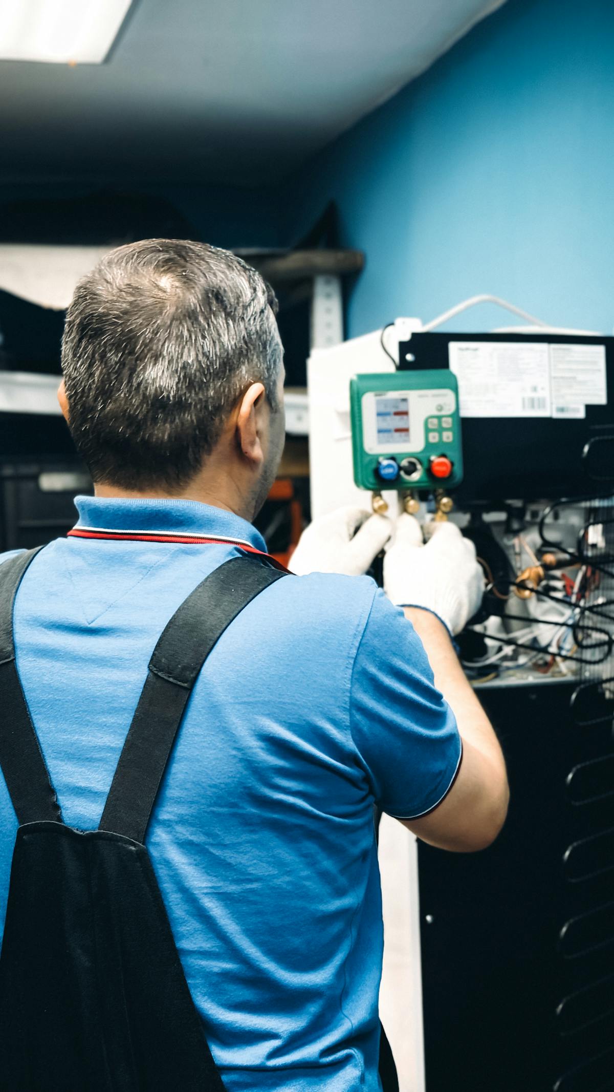 Technician checking refrigerant pressures with manifold gauges