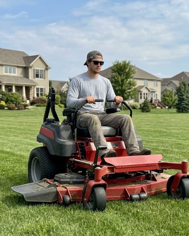Landscaper on a riding mower at a residential property